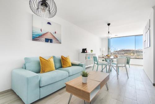a living room with a blue couch and a table at Home2Book Blue Sea View Patalavaca Beach Apartment in Patalavaca