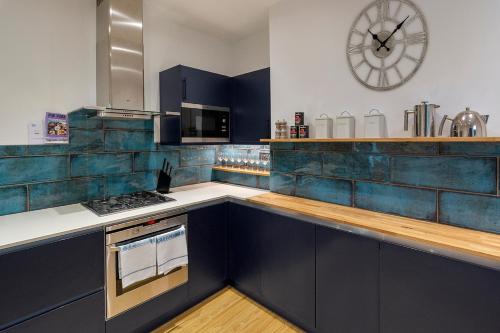 una cocina con armarios azules y un reloj en la pared en Beautiful views! 3 great doubles!, en Bath