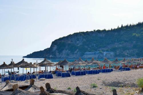 a beach with many chairs and umbrellas and the ocean at Alex & Sofi Hotel in Himare