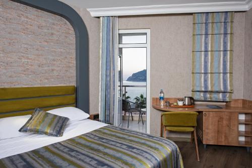 a hotel room with a bed and a desk and a window at Monart City Hotel - All Inclusive Plus in Alanya