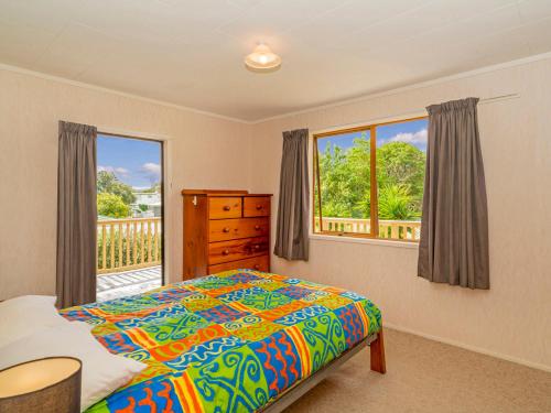 a bedroom with a bed and a window at Oyster Bach - Cooks Beach Bach in Cooks Beach