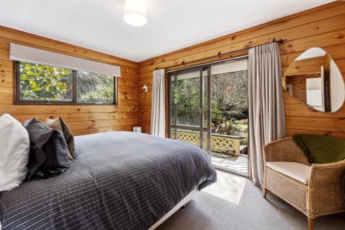 a bedroom with a bed and a large window at River Road Spa Lodge - Broadlands Forest in Taupo