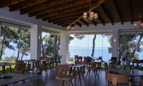 a restaurant with tables and chairs and large windows at Country Inn in Kallithea Halkidikis