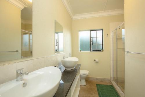 a white bathroom with a sink and a toilet at Kruger's Retreat House & Kruger's Rest Studio in Marloth Park