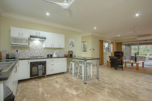 a kitchen with white cabinets and a black counter top at Kruger's Retreat House & Kruger's Rest Studio in Marloth Park