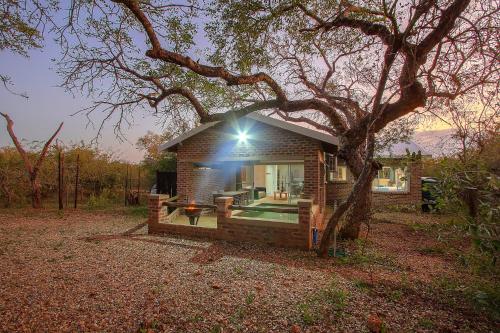 a small house with a tree in front of it at Kruger's Retreat House & Kruger's Rest Studio in Marloth Park