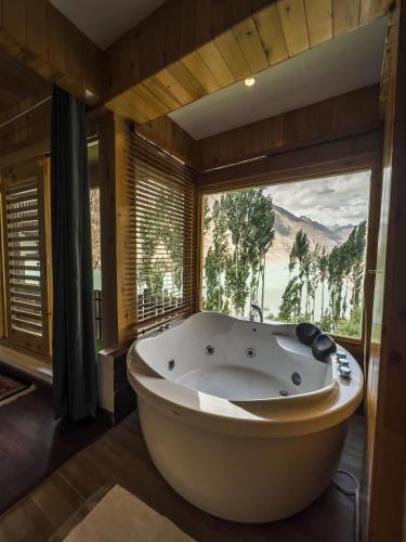 a large bath tub in a room with a large window at Famree Resort Hunza in Hunza Valley