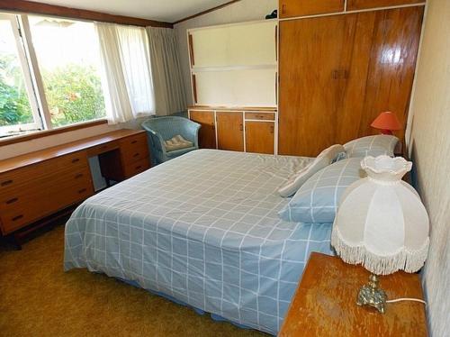 a bedroom with a bed and a desk and window at Hibiscus Cottage - Whangamata Bach in Whangamata