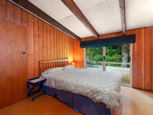 a bedroom with a bed and a large window at Te Kuru Cabin - Pukawa Bay Holiday Home in Kuratau