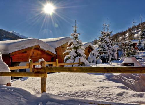 a house covered in snow with the sun in the background at Villaggio Gofree in Pragelato