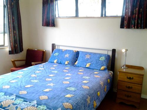 a bedroom with a bed with a blue comforter at The Sands - Matarangi Holiday House in Matarangi