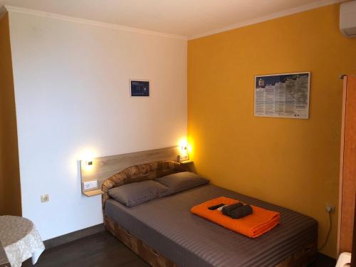 a bedroom with a bed with an orange blanket on it at Apartments PEHAR in Podaca