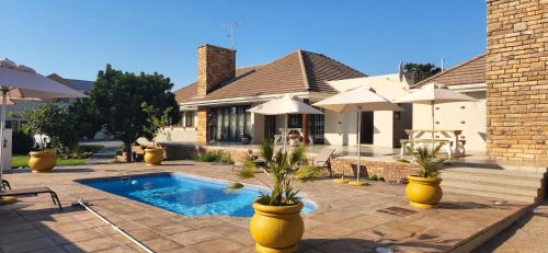 a house with a swimming pool with two potted plants at Avanti Guest Lodge in Vredenburg