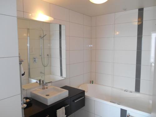 Baño blanco con lavabo y bañera en Absolute Waterfront, Tauranga Apartment, en Tauranga