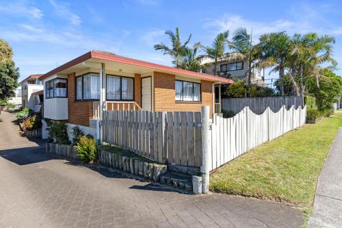 a house with a fence in front of it at At The Mount - Mt Maunganui Holiday Home in Mount Maunganui