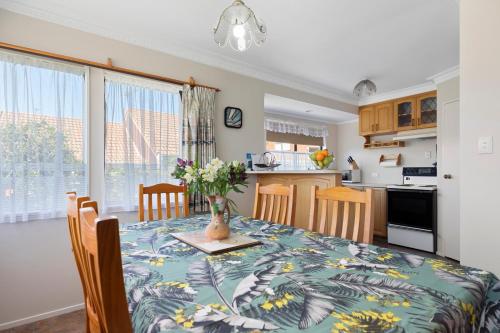a kitchen and dining room with a table with flowers on it at At The Mount - Mt Maunganui Holiday Home in Mount Maunganui