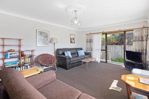 a living room with a couch and a television at At The Mount - Mt Maunganui Holiday Home in Mount Maunganui