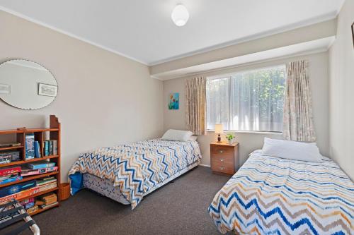 een slaapkamer met 2 bedden naast een raam bij At The Mount - Mt Maunganui Holiday Home in Mount Maunganui