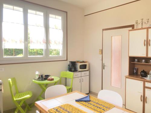 a kitchen with a table and chairs and a small table with a microwave at Halte Saltusienne in Saint-Julien-du-Sault