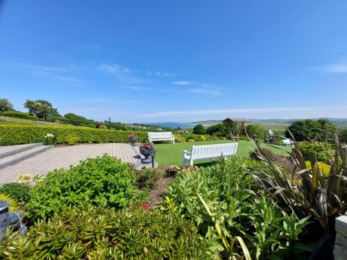 eine weiße Bank, die in einem Garten mit Rasen sitzt in der Unterkunft The Ballyliffin Lodge and Spa in Ballyliffin