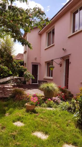 une maison rose avec des fleurs dans la cour dans l'établissement Chambre, avec accès à la cuisine, et au jardin calme, à La Copechagnière