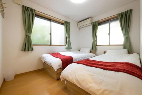 two beds in a room with two windows at 田端民泊ー田端ハウス in Tokyo