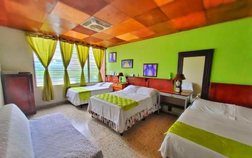 a bedroom with two beds and a green wall at Hotel Oasis in San Salvador