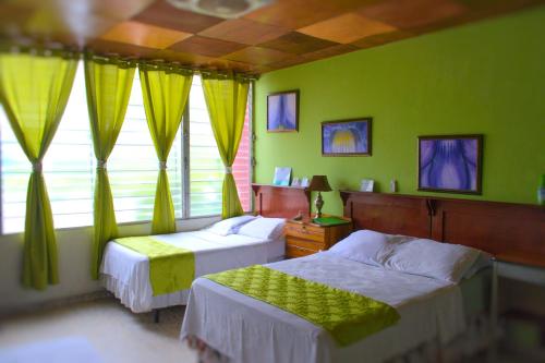 two beds in a bedroom with green walls and windows at Hotel Oasis in San Salvador