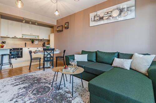 a living room with a green couch and a kitchen at Апартаменти Ивайло / Ivaylo apartments in Burgas City
