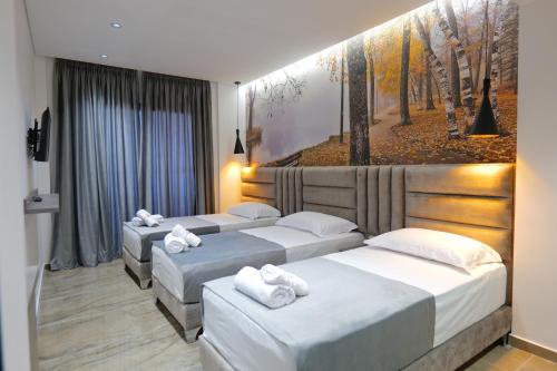 three beds in a hotel room with towels on them at Hotel Eagle in Ksamil