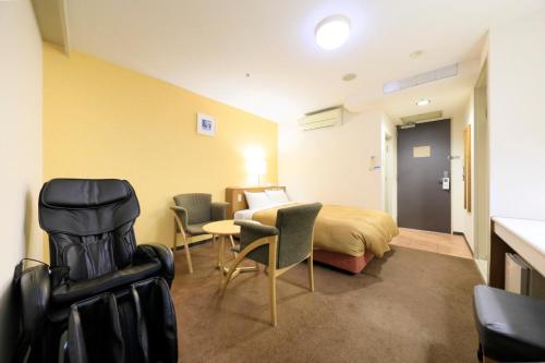 a hotel room with a bed and a table and chairs at Bell's Inn Tsuchiura in Tsuchiura