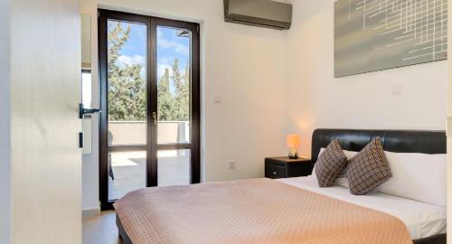 1 dormitorio con 1 cama y puerta con ventana en Villa Delphin 375 Fantastic villa with amazing outside space, Aphrodite Hills, en Kouklia