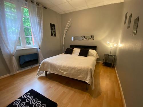 Hôtel restaurant l'escale chez mimi في Bioule: غرفة نوم بسرير ذو شراشف بيضاء ومخدات سوداء