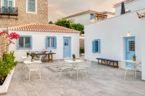 eine Terrasse mit Tischen und Stühlen und ein Gebäude in der Unterkunft Lumiére spetses in Spetses