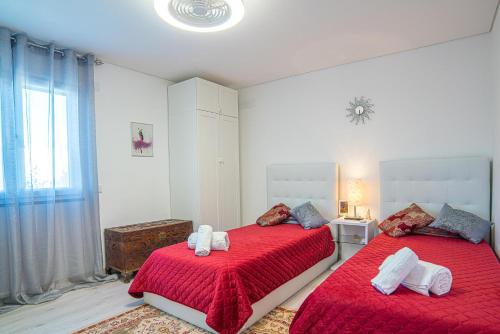 Un dormitorio con dos camas con sábanas rojas y una ventana. en Villa Santi, en Aroeira