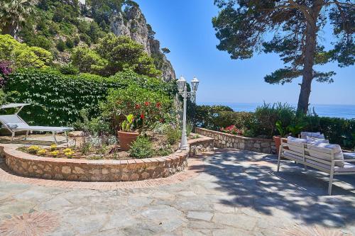 een patio met 2 banken en bloemen en de oceaan bij To Be Capri Sea view Rooms in Capri