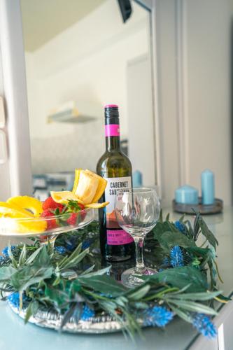 a bottle of wine and a bowl of fruit and a glass at RODI BLUE apartments in Amoudara Herakliou