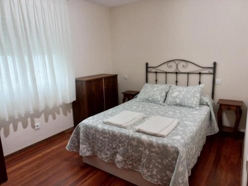 a bedroom with a bed with two towels on it at Apartamento Catalina, céntrico, tranquilo y luminoso in Llanes