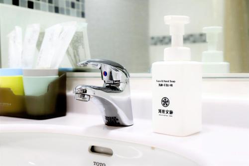 a bathroom sink with a faucet and a bottle of soap at Holo Hotel Tainan in Tainan