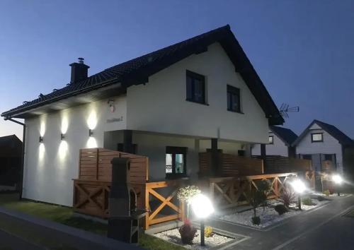 a white house with lights in front of it at Delfinek - Domki Apartamenty in Gąski