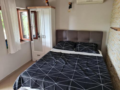 um quarto com uma cama com um edredão preto e branco em Studio apartment Ivan em Čunski