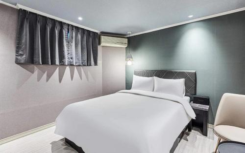 a bedroom with a large white bed and a chair at Hotel WO Yongsan Station in Seoul