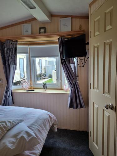 Foryd的住宿－Goldensands，一间卧室设有一张床和一个带电视的窗户。