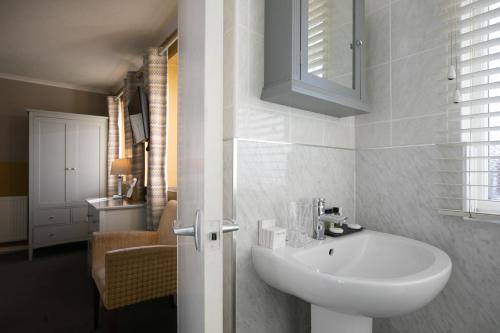 La salle de bains blanche est pourvue d'un lavabo et d'un miroir. dans l'établissement Castlemead Country House By The Sea, à Manorbier