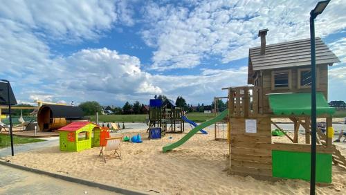a playground with play equipment in the sand at Resorts H Białka Tatrzańska z sauną, Sun & Snow in Białka Tatrzanska