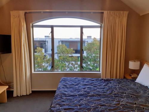a bedroom with a bed and a large window at Apartment Fourteen in Taupo