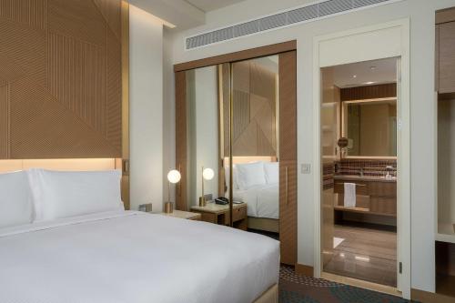 a bedroom with a white bed and a bathroom at Slemani Rotana in As Sulaymānīyah