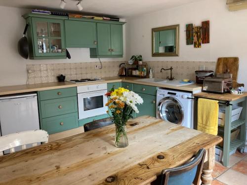 une cuisine avec une table et un vase de fleurs. dans l'établissement Charming Cottage, Central Taunton., à Taunton