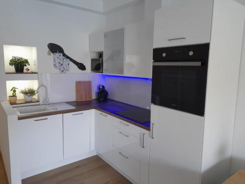 uma cozinha com armários brancos e electrodomésticos pretos em Apartments Palma em Polace