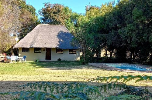 a house with a thatched roof and a pool at Brentwood Lodge in Denysville